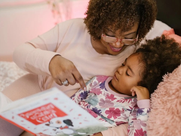 Young woman reading with little girl